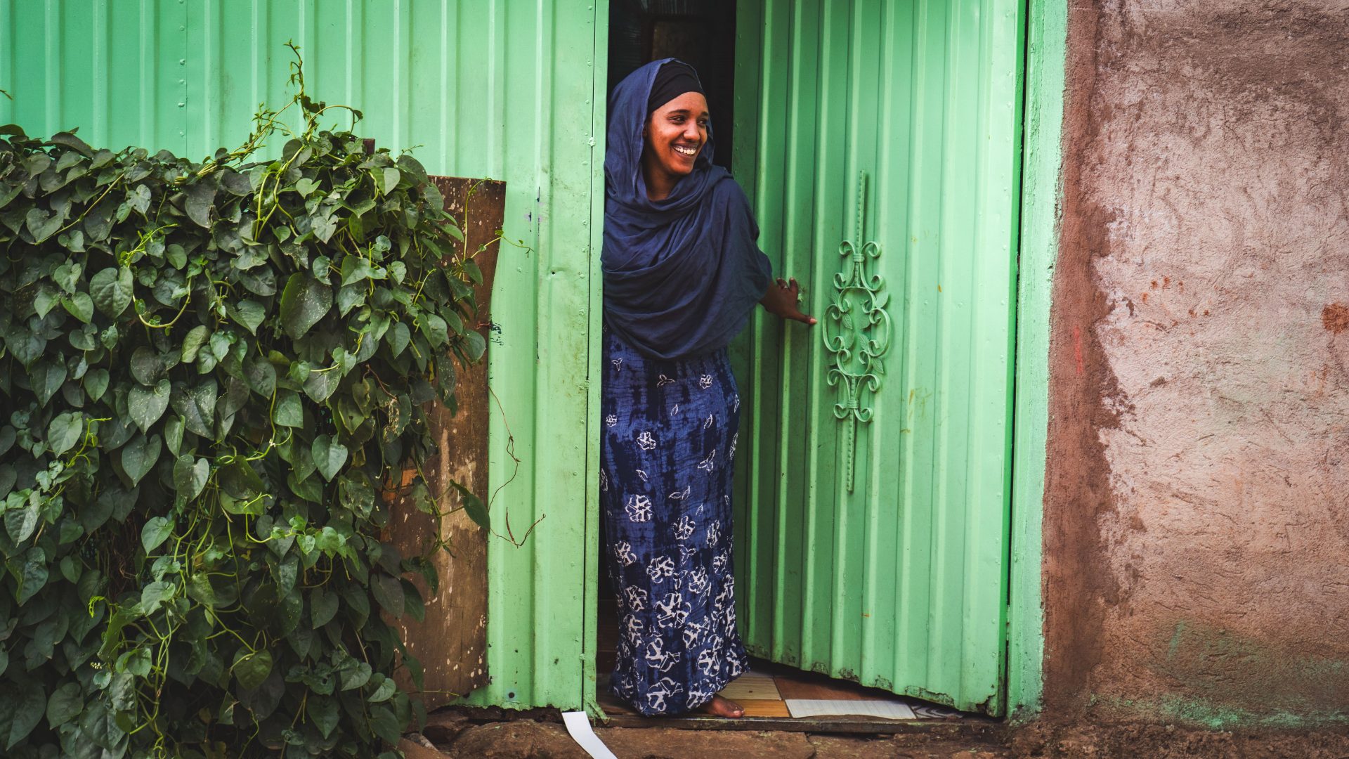 A woman at the doorway of her home in Ethiopia, smiling